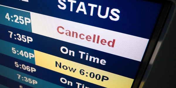 Airport flight information display showing a cancelled flight among scheduled departures, highlighting the importance of staying informed about flight updates, schedule changes, and alternative travel options.