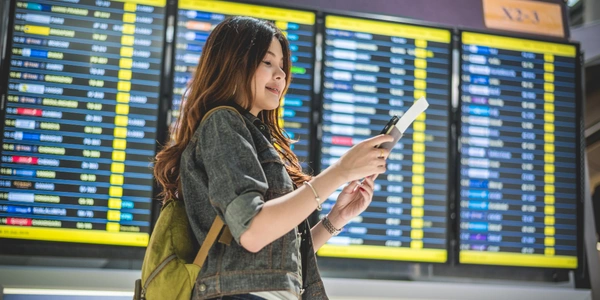 A traveler reviews flight information at the airport while searching for affordable Malaysia Airlines tickets and the latest flight deals for upcoming travel plans.
