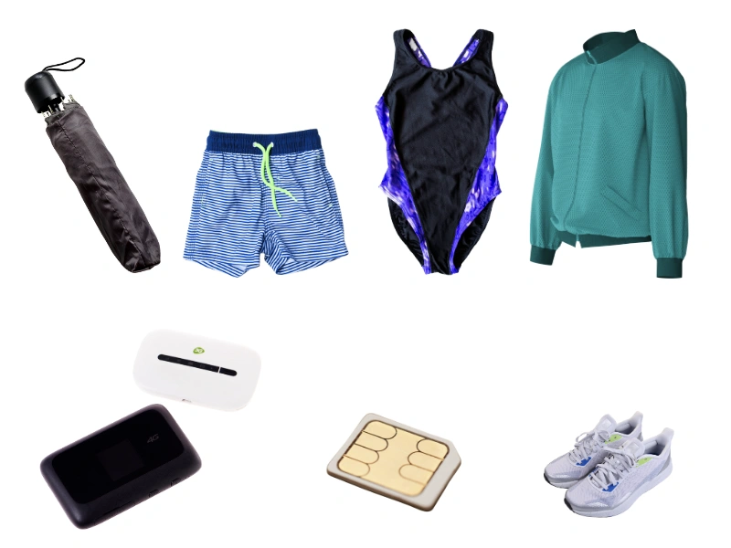 Assorted travel essentials laid out for packing, including striped shorts, a swimsuit, green jacket, umbrella, portable Wi-Fi device, power bank, flip-flops, and white sneakers with blue accents.