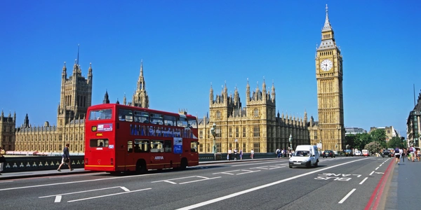 Red double-decker bus crossing Westminster Bridge with Big Ben and the Palace of Westminster in London, United Kingdom, a popular international destination accessible via Malaysia Airlines flights.