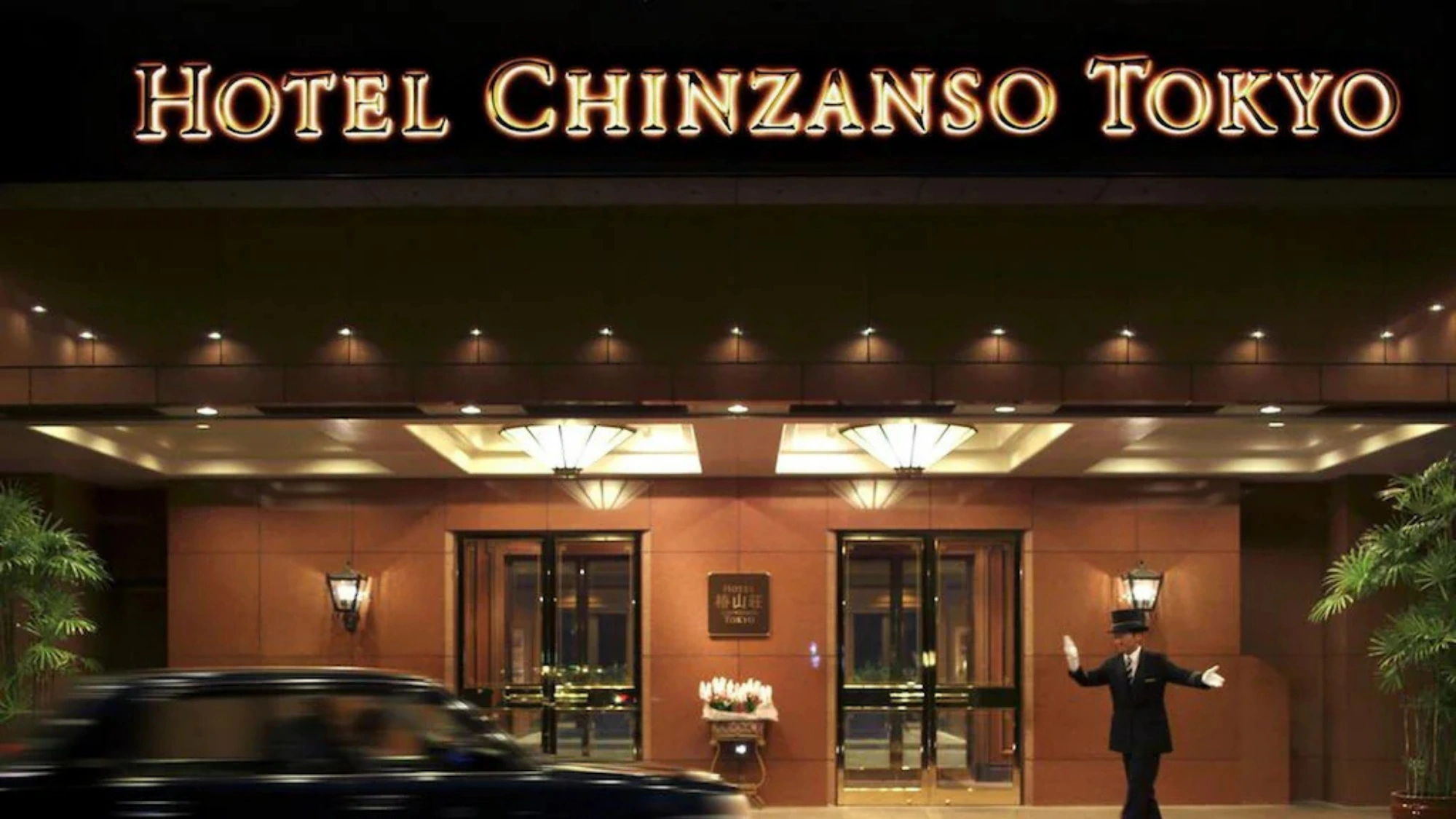 The grand, lit entrance of Hotel Chinzanso Tokyo at night with a uniformed doorman and classic car.