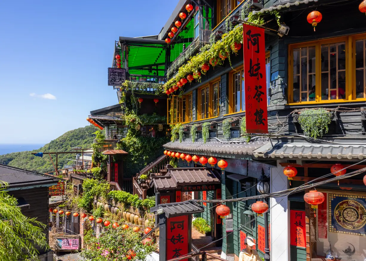 Crowded Shifen Old Street in Taiwan with tourists releasing colorful sky lanterns from railway tracks, surrounded by traditional shops and mountainous scenery. A popular cultural destination known for its lantern tradition and nearby waterfall.