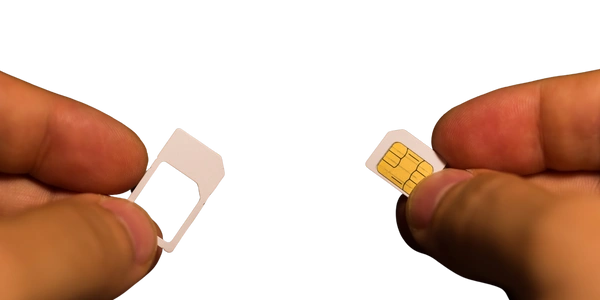 Two hands holding a SIM card and a SIM card adapter; the left hand holds the empty adapter frame, while the right hand holds the SIM card with visible gold contacts.