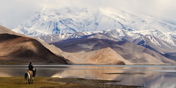 Karakul Lake in Xinjiang, China, reflecting snow-capped mountains and rugged high-altitude landscapes, a breathtaking eco-tourism destination along the ancient Silk Road.