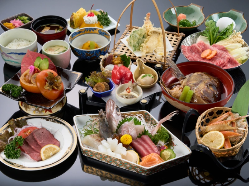 Traditional Japanese kaiseki meal featuring elegantly arranged multi-course dishes including sashimi, tempura, grilled fish, soup, rice, and pickled vegetables, served in a variety of artistic plates and bowls.