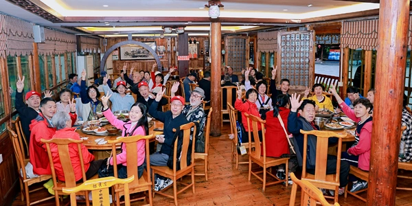 Large tour group enjoying a traditional banquet meal at a local wooden lodge during a Meet You Train vacation.
