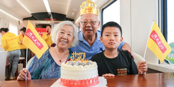 Elderly couple celebrating a birthday with family inside a private cabin on the Meet You Train.