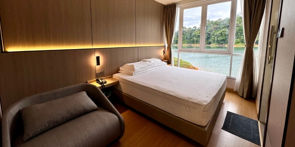 A modern houseboat bedroom at Tasik Kenyir with a large window showing a view of the lake and lush green trees