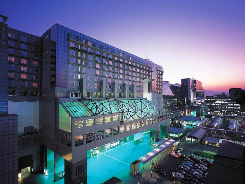 Hotel Granvia Kyoto at twilight with a glass-roofed section and surrounding cityscape.