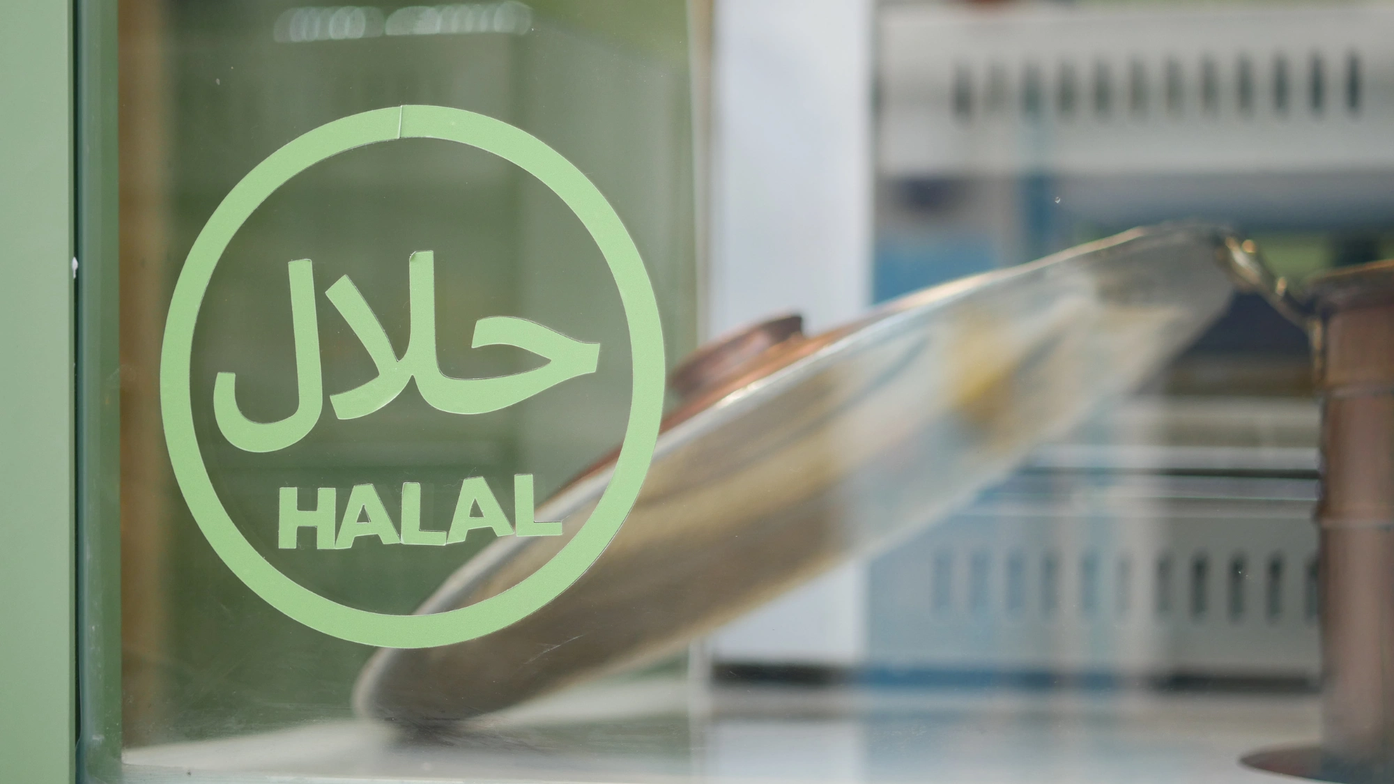 A close-up of a circular green Halal certification sticker on a glass window in Japan.