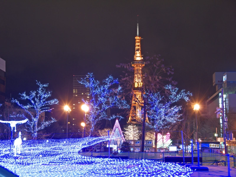 Sapporo TV Tower lit up at night with festive blue and white lights.